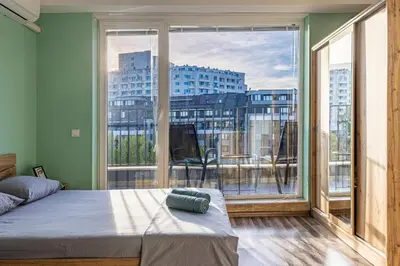 a bedroom with a bed and a large window at Ishirkov Residence Studio With Mountain VIew Balcony and Underground Parking in Sofia