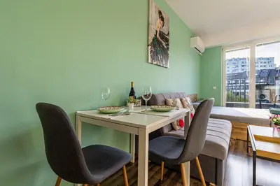 a living room with a table with chairs and a couch at Ishirkov Residence Studio With Mountain VIew Balcony and Underground Parking in Sofia