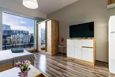 a living room with a tv and a large window at Ishirkov Residence Studio With Mountain VIew Balcony and Underground Parking in Sofia