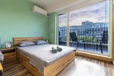 a bedroom with a bed and a large window at Ishirkov Residence Studio With Mountain VIew Balcony and Underground Parking in Sofia
