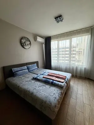 a bedroom with a bed with blue pillows and a window at Gabana apartments in Sofia