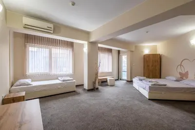 two beds in a room with two windows at Yubim rooms in Sofia