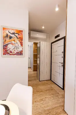 a room with a hallway with a white chair and a painting on the wall at Elena apartment in Sandanski