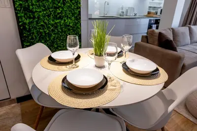 a white dining room table with chairs and wine glasses at Elena apartment in Sandanski