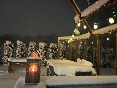 a snow covered porch with a bed and a lantern at Villa Stemara in Razlog
