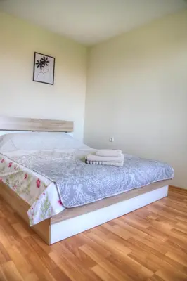 a bed in a white room with a wooden floor at Nevena 206 B&P in Bansko