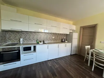 a kitchen with white cabinets and a table with chairs at 63rd Luxury One Bedroom Apartment in Sofia