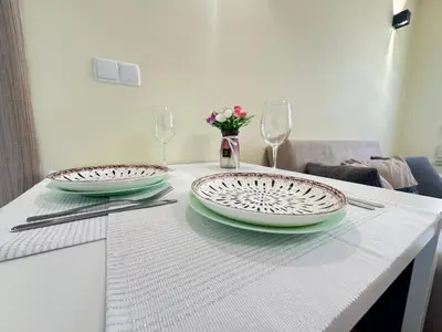 a white table with two plates and glasses and flowers at 63rd Luxury One Bedroom Apartment in Sofia