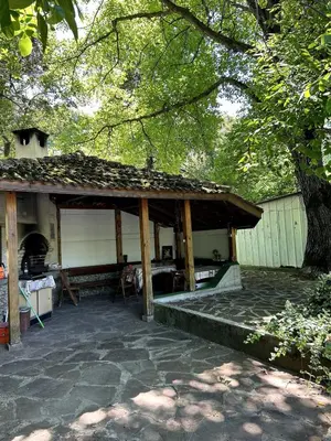 a pavilion with a stone patio and a tree at Guest House Efrosina in Glozhene