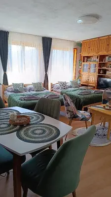 a living room with two beds and a table and chairs at Родопско сърце in Chepelare