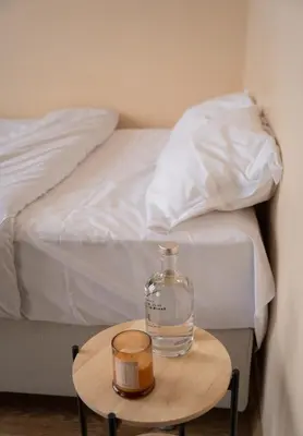 a glass bottle on a table next to a bed at Paradise Nest in Sofia