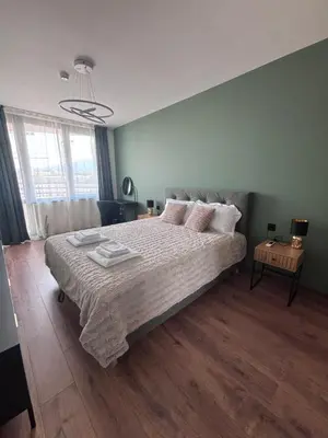 a bedroom with a large bed with a wooden floor at Atana Home Drujba in Sofia