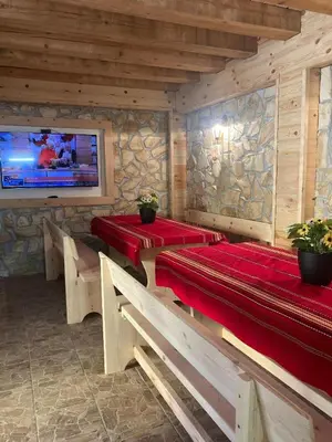 a dining room with two tables and benches and a tv at Guest house Dinaya-2 in Dobrinishte