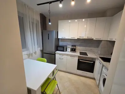 a kitchen with white cabinets and a table and a refrigerator at Paradise Studio NBU in Sofia
