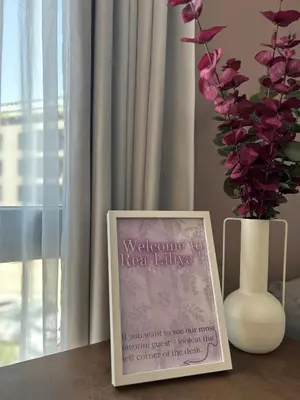a sign sitting on a table next to a vase with flowers at Rea Liliya - Artistic and Inviting Nook in Sofia
