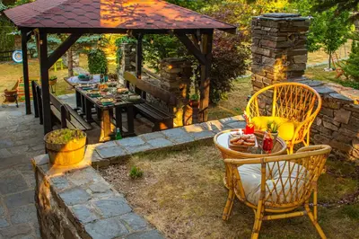 a table and chairs under a gazebo with a table and a bench at Дедовата Къща in Dedovo