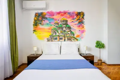 a bedroom with a white bed with a painting on the wall at Spacious 3BR in the Center - Kitchen Smart TV's in Sofia