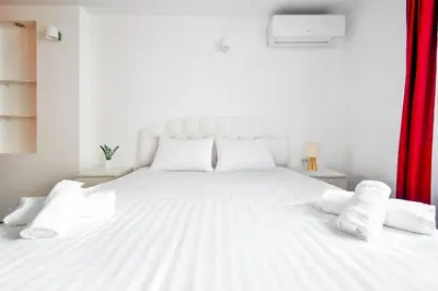 a white bed with white pillows and a red curtain at Spacious 3BR in the Center - Kitchen Smart TV's in Sofia