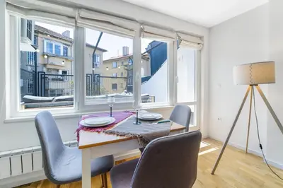a dining room with a table and chairs and windows at Charming Downtown Apartment with Unique Terrace in Sofia