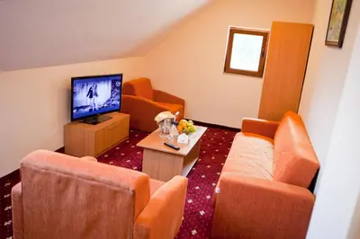 a living room with orange chairs and a television at Hotel Coop Rozhen in Pamporovo
