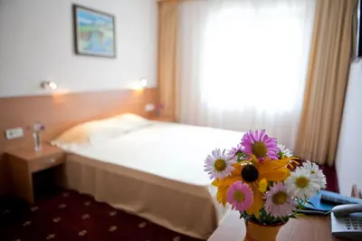 a hotel room with a bed and a vase of flowers at Hotel Coop Rozhen in Pamporovo