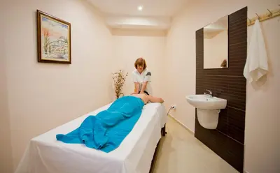 a woman sitting on a bed in a hospital room at Hotel Coop Rozhen in Pamporovo