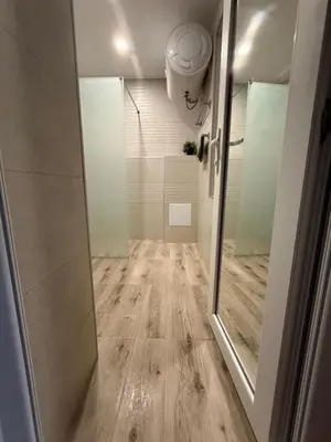 a bathroom with a shower and a wooden floor at Нощувки 