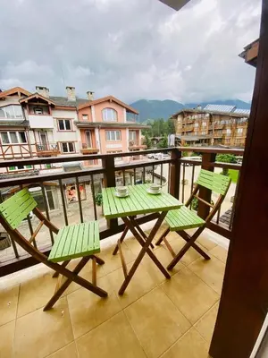 a balcony with a table and chairs on a balcony at Pirin Golf Spa Condo with Mountain View in Razlog