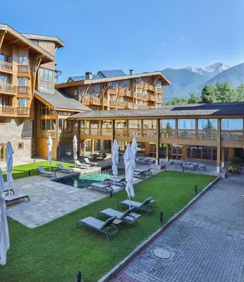 a resort with lounge chairs and a pool and a building at Pirin Golf Spa Condo with Mountain View in Razlog