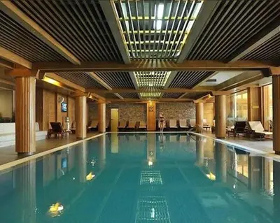 a swimming pool in a building with a person standing in it at Pirin Golf Spa Condo with Mountain View in Razlog