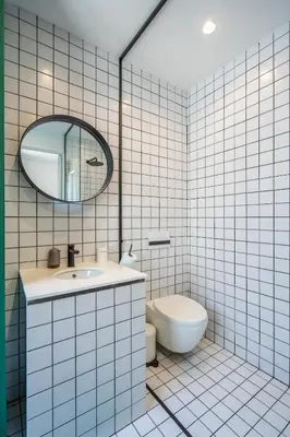 a white tiled bathroom with a sink and a toilet at Bright & Central 2BR in Historic Heart of Sofia in Sofia
