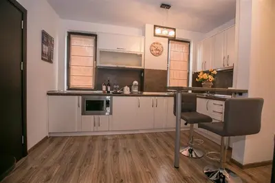 a kitchen with white cabinets and a table and a chair at В Сандански есента идва с топлина, слънце и златна светлина in Sandanski