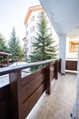 a balcony with a wooden fence with trees on it at Alpine Escape Design apartment Detelina Residence in Bansko