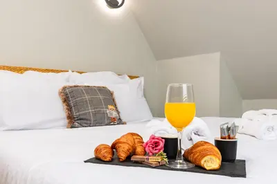 a tray of croissants and a glass of orange juice on a bed at Central Apartments with Garden view by Flat Mаnager in Plovdiv