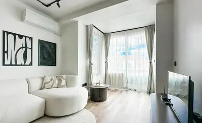 a living room with a white couch and a large window at Modern & Quiet 1BR Near Center by Flat Mаnager in Sofia