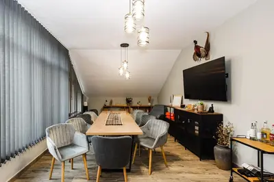 a dining room with a table and chairs and a tv at Вила Тих кът in Resilovo