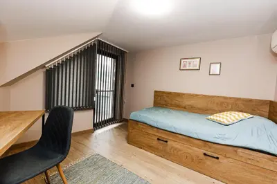 a bedroom with a bed and a desk and a chair at Вила Тих кът in Resilovo