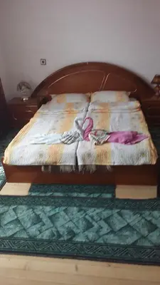 a bed with a wooden headboard with clothes on it at Guest House Jani in Trigrad