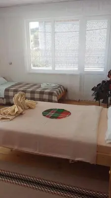 two beds in a room with two windows at Guest House Jani in Trigrad