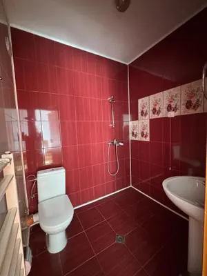 a red tiled bathroom with a toilet and a sink at Stenata LightWill in Banya