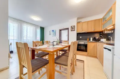 a kitchen and dining room with a wooden table and chairs at Тристаен апартамент 1А17 Гранд Манастира Пампорово in Pamporovo