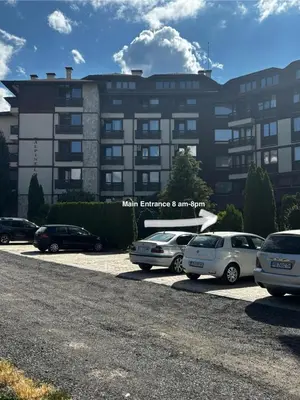 a large building with cars parked in a parking lot at Alpine Lodge Chalet in Bansko in Bansko