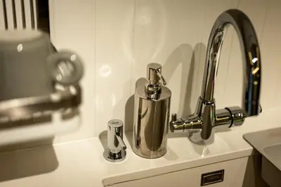a kitchen sink with a faucet and two cups at Private Premium Apartment in Plovdiv in Plovdiv