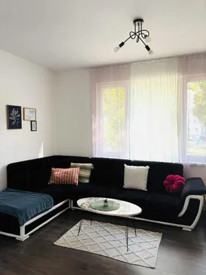 a living room with a black couch and a table at Spacious&Cousy 3 bedroom apartment in Plovdiv