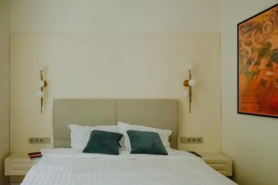 a bedroom with a white bed with two green pillows at Elegant Escape-High Ceilings, Balcony & Piano by Flat Mаnager in Sofia