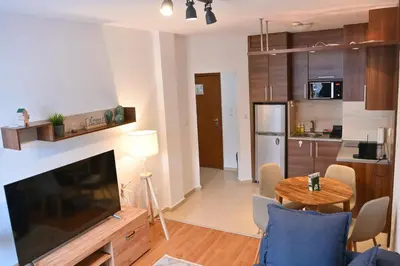 a living room with a large television and a kitchen at Cozy Flat with Pool & Mountain Views, Near Gondola by Flat Mаnаger in Bansko