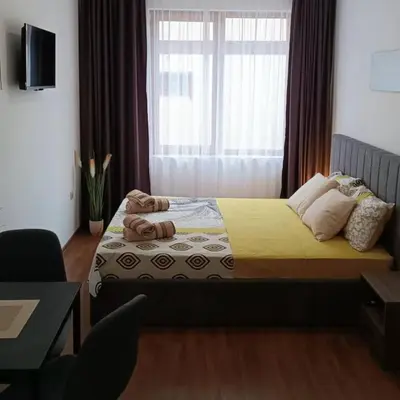 a bedroom with a bed with a yellow blanket and a window at Bella apartment Bansko in Bansko