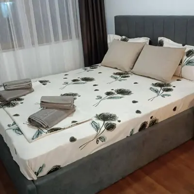a bed with a white blanket with flowers on it at Bella apartment Bansko in Bansko