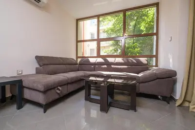 a living room with a couch and a large window at 2-Bedroom Apartment in the City Center in Plovdiv