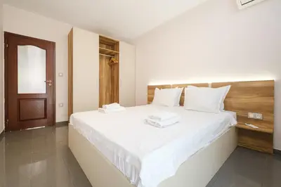 a bedroom with a large white bed with a wooden headboard at 2-Bedroom Apartment in the City Center in Plovdiv
